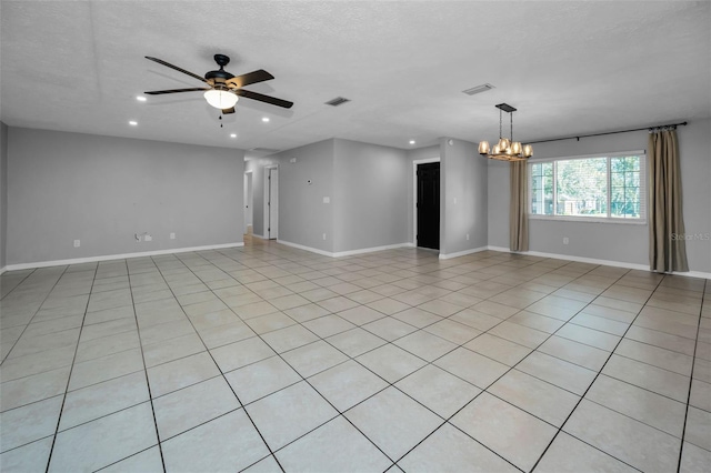 spare room with a textured ceiling, light tile patterned flooring, and ceiling fan with notable chandelier