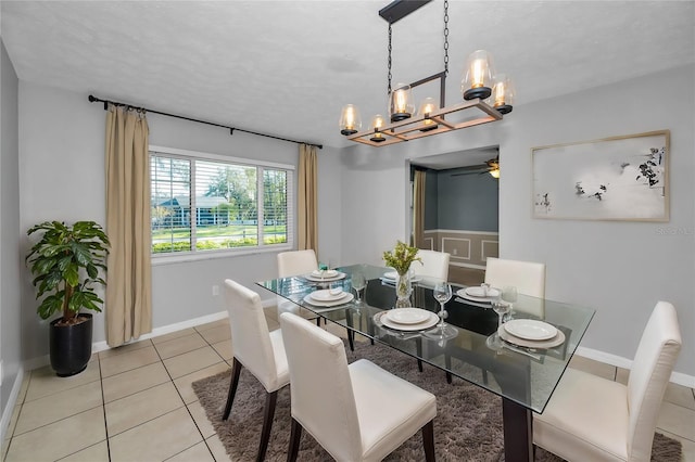 dining area with a textured ceiling, light tile patterned floors, and ceiling fan with notable chandelier