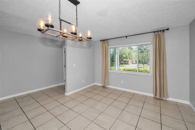 spare room with a notable chandelier, light tile patterned floors, and a textured ceiling