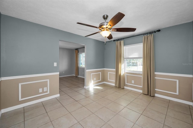 empty room with ceiling fan, plenty of natural light, and light tile patterned flooring