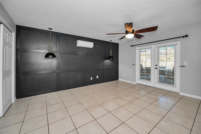 spare room featuring an AC wall unit, french doors, light tile patterned floors, and a textured ceiling