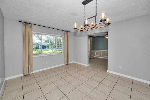 tiled spare room with ceiling fan with notable chandelier and a textured ceiling