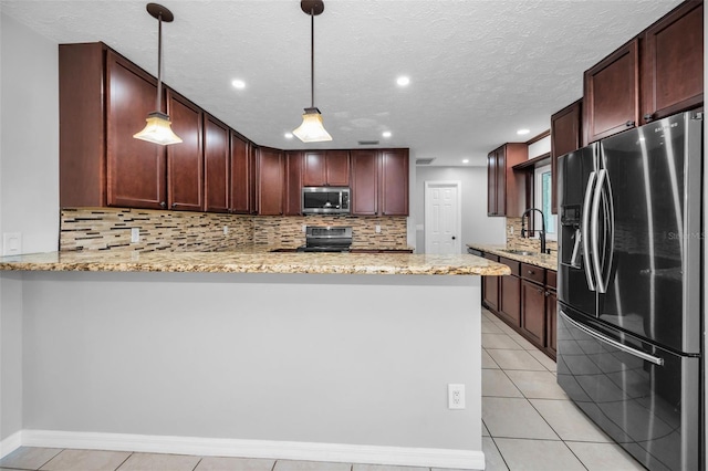 kitchen featuring kitchen peninsula, appliances with stainless steel finishes, and pendant lighting