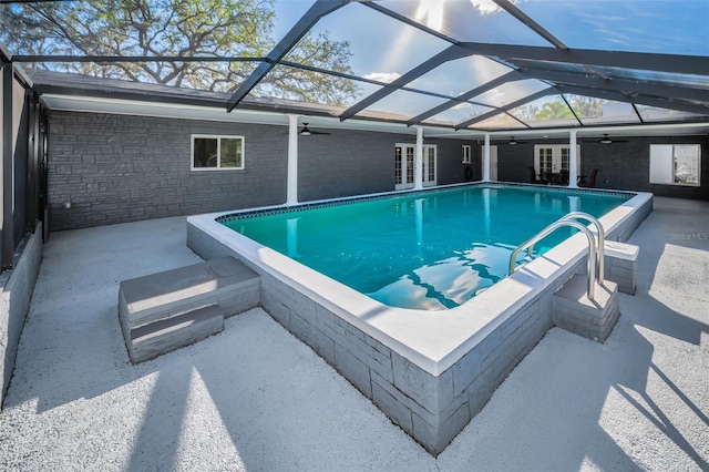 view of swimming pool with glass enclosure, ceiling fan, and french doors