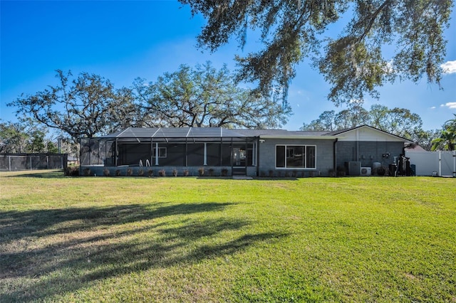 rear view of property with glass enclosure and a yard