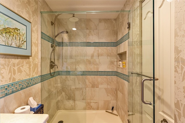 bathroom with vanity, a shower with door, and tile walls