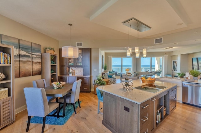 kitchen with light wood-type flooring, stainless steel dishwasher, a water view, a kitchen island, and hanging light fixtures