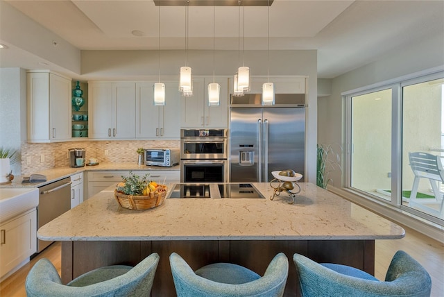 kitchen with white cabinetry, light hardwood / wood-style flooring, a kitchen island, and appliances with stainless steel finishes