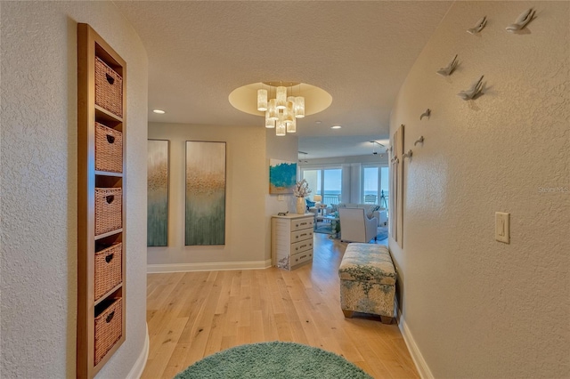 hall with light hardwood / wood-style floors and a textured ceiling