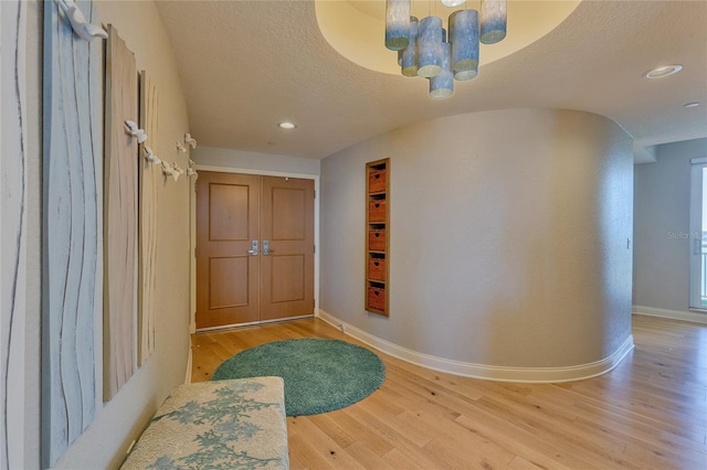 entrance foyer featuring wood-type flooring, a textured ceiling, and an inviting chandelier