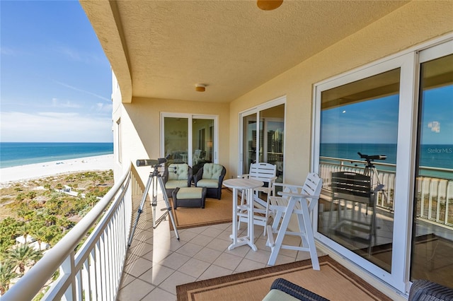 balcony featuring a water view and a beach view