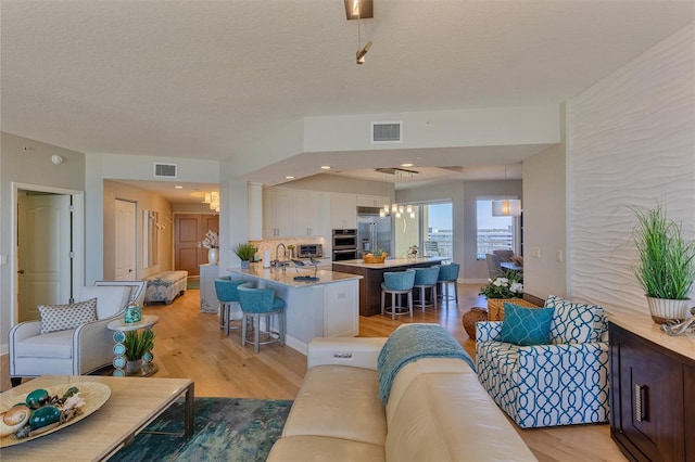 living room featuring a textured ceiling, light hardwood / wood-style floors, and an inviting chandelier