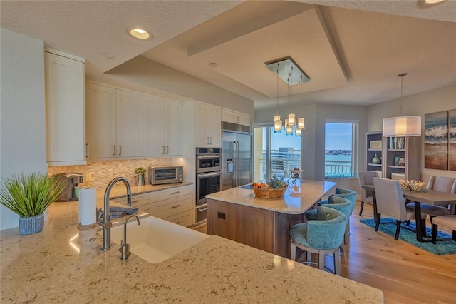 kitchen featuring pendant lighting, white cabinetry, appliances with stainless steel finishes, and sink