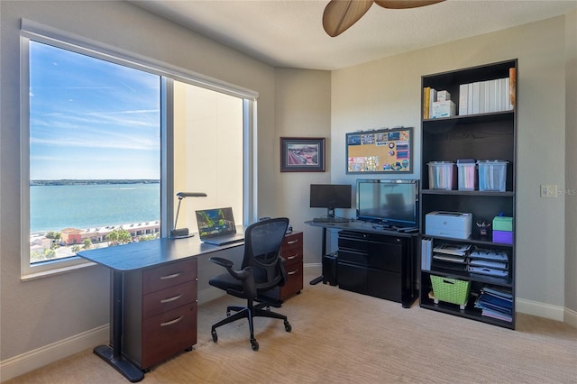 office area featuring ceiling fan, a water view, and light colored carpet