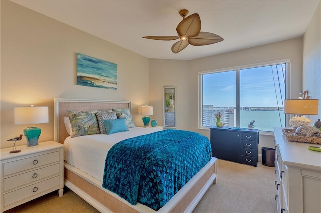 carpeted bedroom featuring ceiling fan and a water view