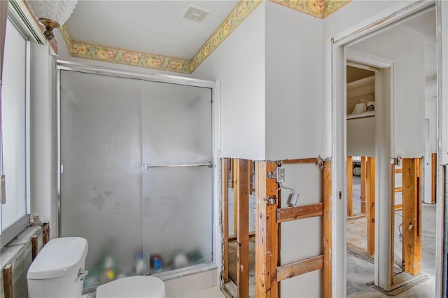 bathroom featuring toilet and a shower with door