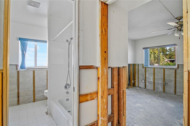 bathroom featuring ceiling fan, toilet, and tub / shower combination