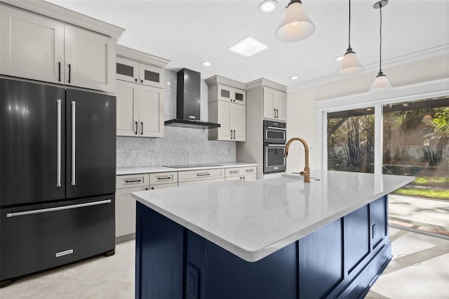 kitchen featuring hanging light fixtures, black appliances, a center island with sink, decorative backsplash, and wall chimney exhaust hood