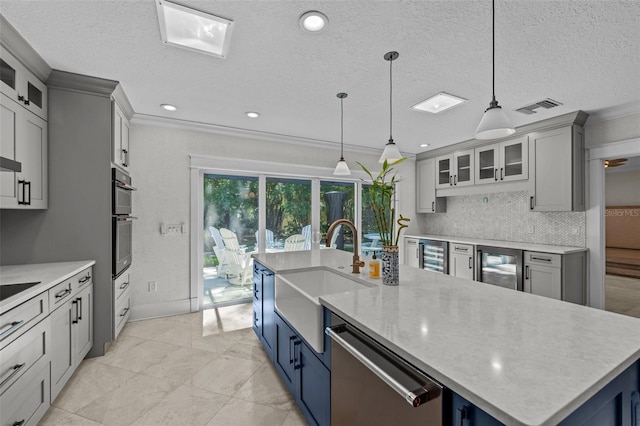 kitchen featuring sink, stainless steel appliances, decorative light fixtures, beverage cooler, and a large island with sink