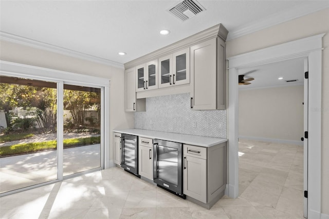 kitchen with wine cooler, crown molding, gray cabinetry, and decorative backsplash