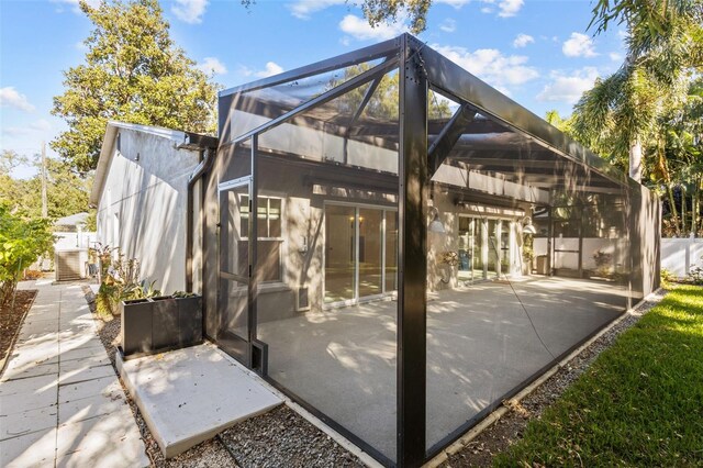 rear view of property with a patio area and glass enclosure