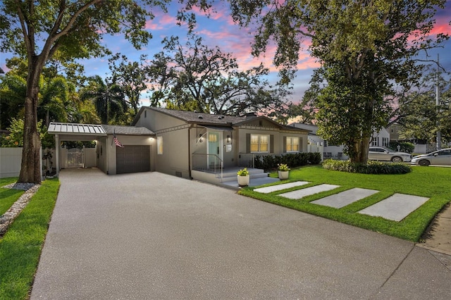 view of front of property featuring driveway, an attached carport, fence, a front lawn, and stucco siding