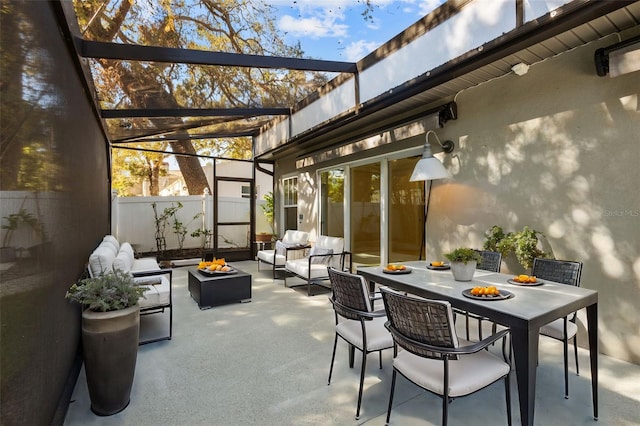 view of patio / terrace featuring glass enclosure, outdoor dining area, fence, and outdoor lounge area