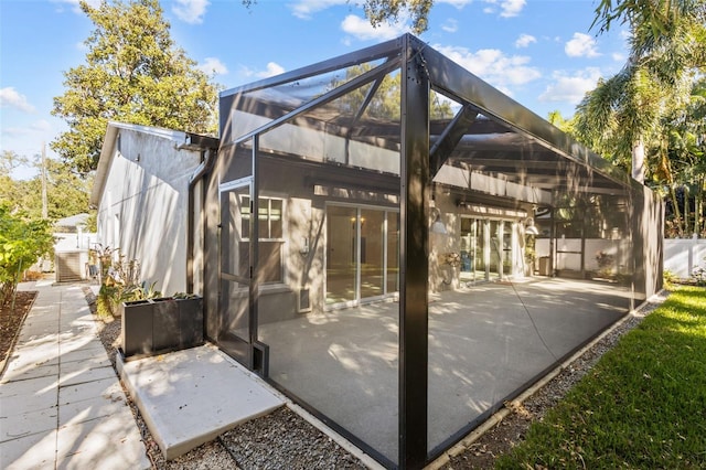 rear view of property with glass enclosure and a patio area