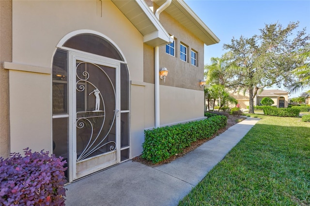 view of exterior entry with a lawn