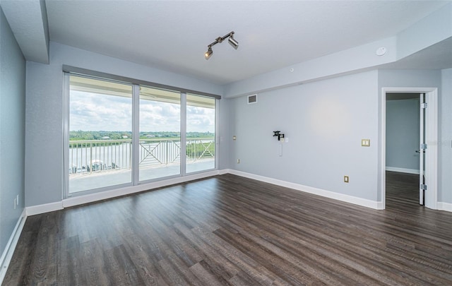 empty room with dark hardwood / wood-style floors and a water view