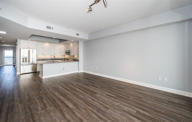 kitchen featuring kitchen peninsula, stainless steel appliances, sink, white cabinets, and dark hardwood / wood-style floors