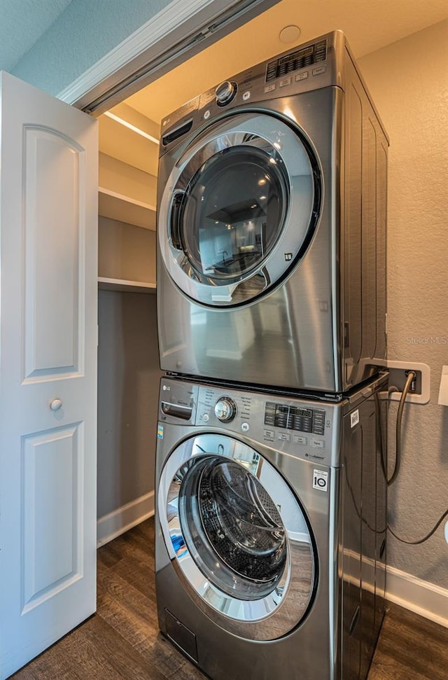 laundry room with dark hardwood / wood-style flooring and stacked washer / drying machine