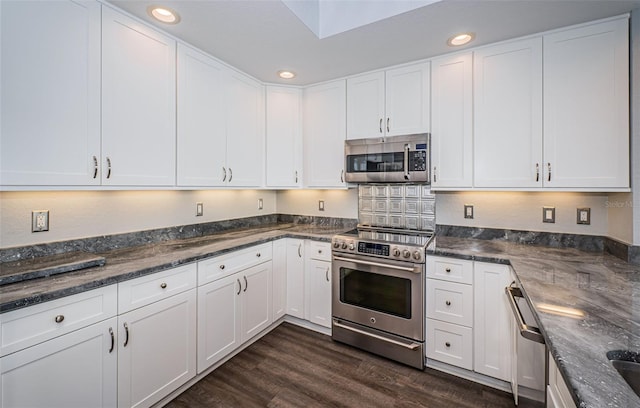 kitchen with white cabinets, dark hardwood / wood-style flooring, dark stone countertops, and appliances with stainless steel finishes