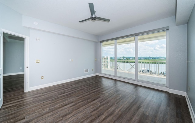 empty room with dark hardwood / wood-style flooring, a water view, and ceiling fan