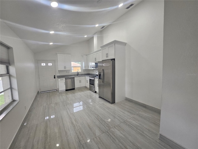 5802 Mohr Loop Unit 5802-5804-5806-5808, Tampa, FL 33615 - kitchen with stainless steel appliances, vaulted ceiling, a sink, white cabinets, and baseboards