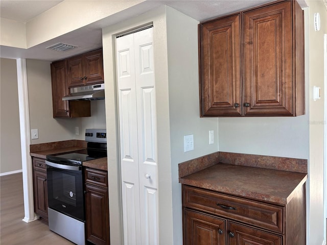 kitchen featuring dark brown cabinetry, light hardwood / wood-style floors, and stainless steel range with electric cooktop