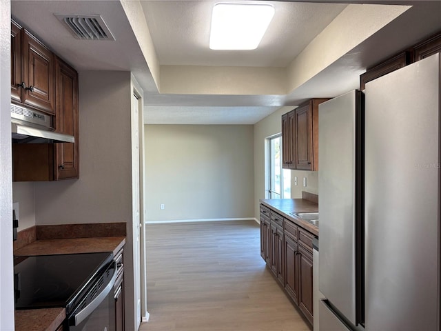 kitchen with black range with electric cooktop, stainless steel fridge, a textured ceiling, and light wood-type flooring