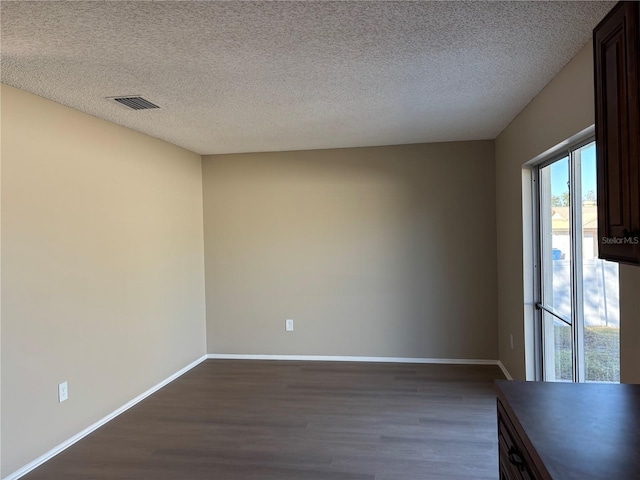 unfurnished room featuring a textured ceiling and dark hardwood / wood-style floors