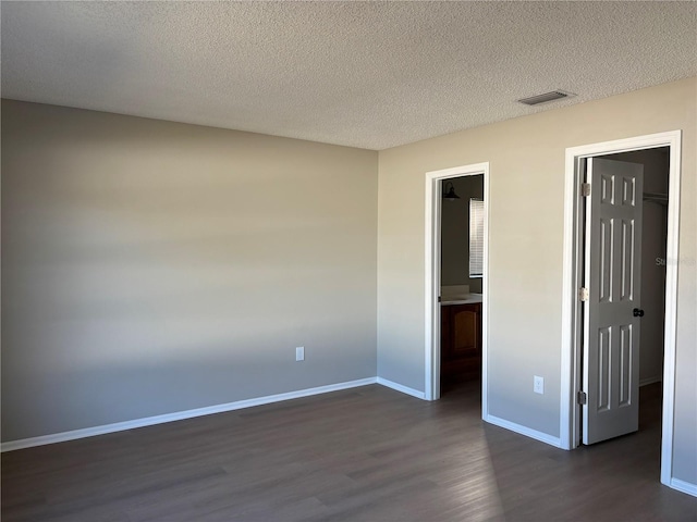 unfurnished room featuring dark hardwood / wood-style floors and a textured ceiling