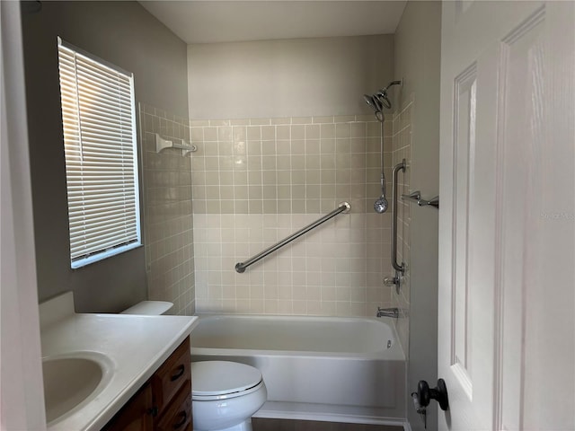 full bathroom featuring vanity, tiled shower / bath combo, and toilet