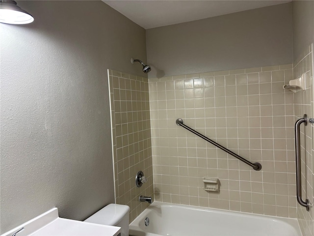 bathroom featuring tiled shower / bath combo and toilet