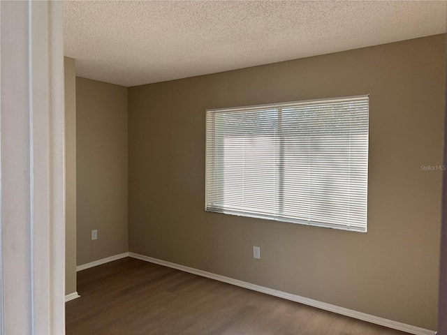 empty room with hardwood / wood-style flooring and a textured ceiling