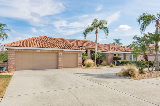 mediterranean / spanish house with an attached garage, a tile roof, and concrete driveway