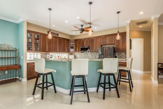 kitchen with stainless steel appliances, a kitchen island with sink, pendant lighting, light tile patterned floors, and a breakfast bar area