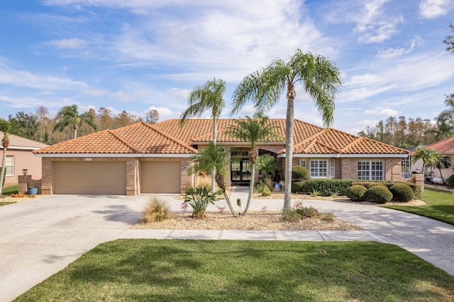 mediterranean / spanish-style house featuring a front lawn, concrete driveway, brick siding, and an attached garage