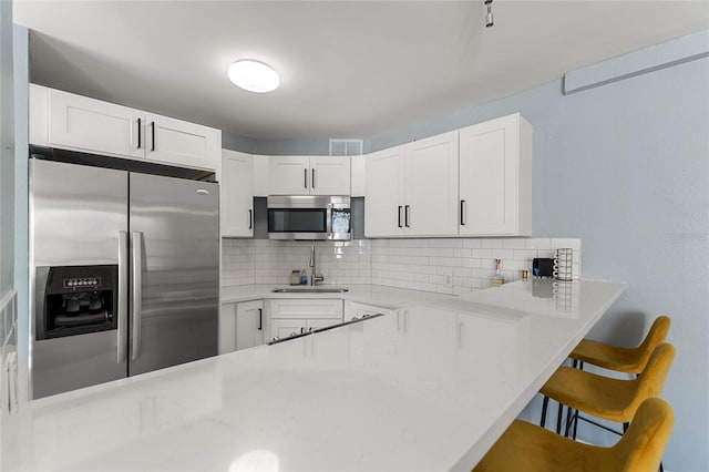 kitchen featuring white cabinets, kitchen peninsula, sink, and appliances with stainless steel finishes