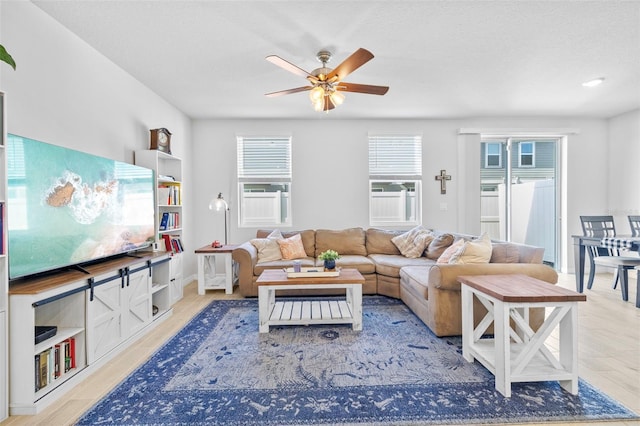 living room featuring a textured ceiling, light hardwood / wood-style flooring, and ceiling fan