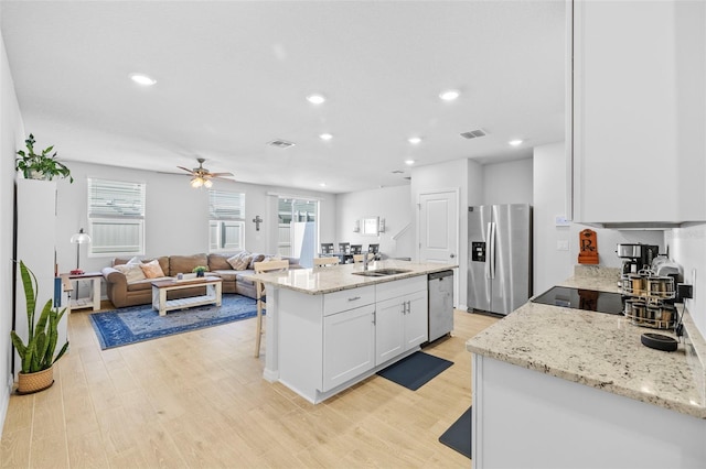 kitchen featuring visible vents, stainless steel appliances, light wood-type flooring, white cabinetry, and a sink