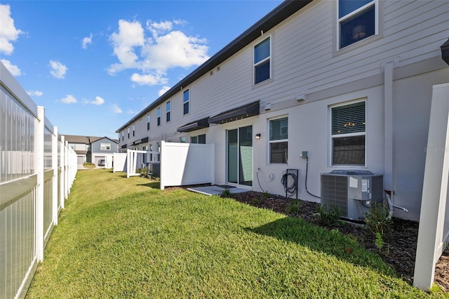 back of property with a lawn and central air condition unit