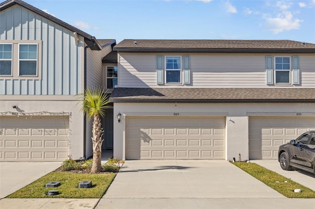 multi unit property featuring driveway, a garage, board and batten siding, and stucco siding